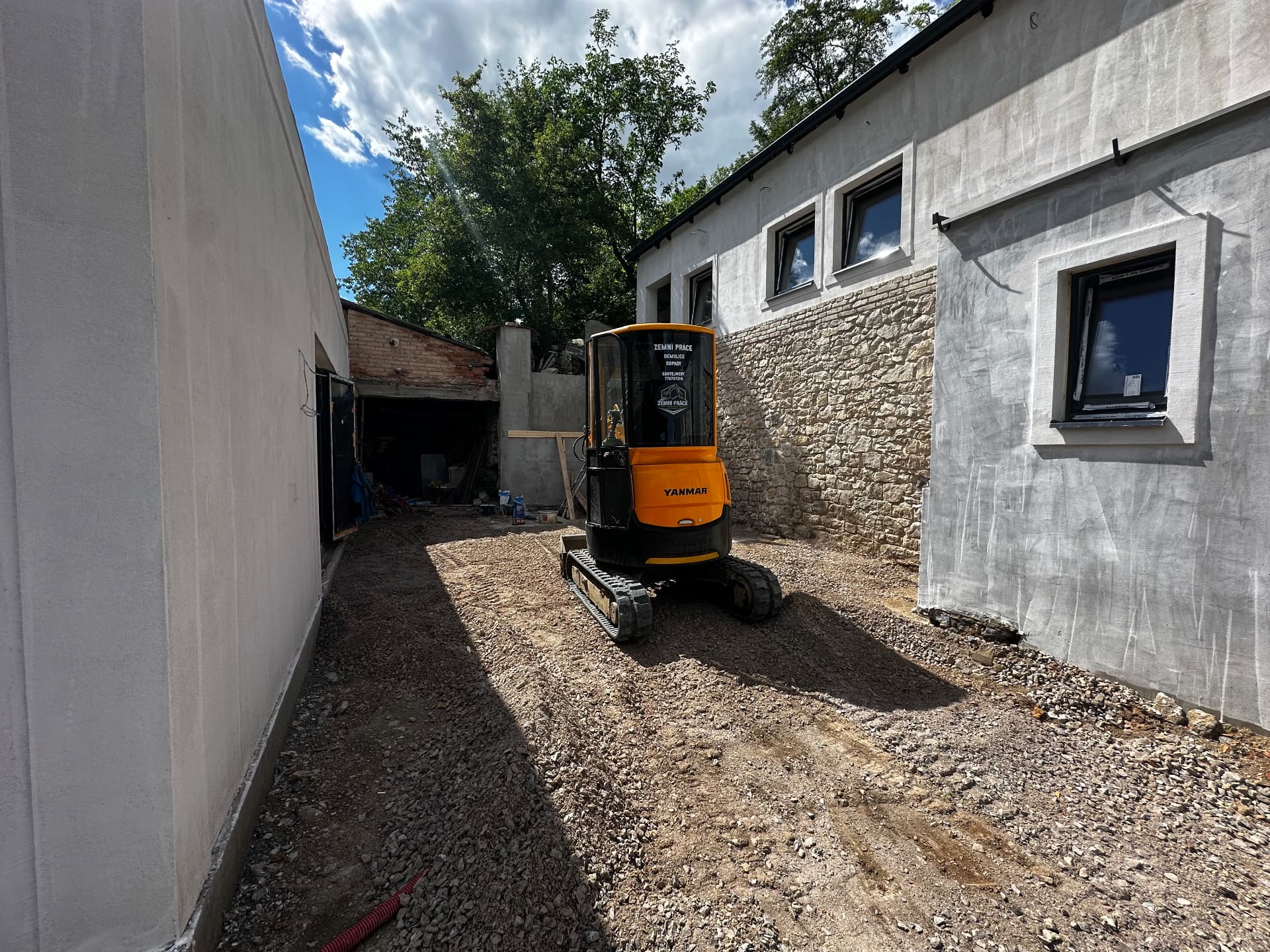 Příprava podkladu minibagrem mezi budovami